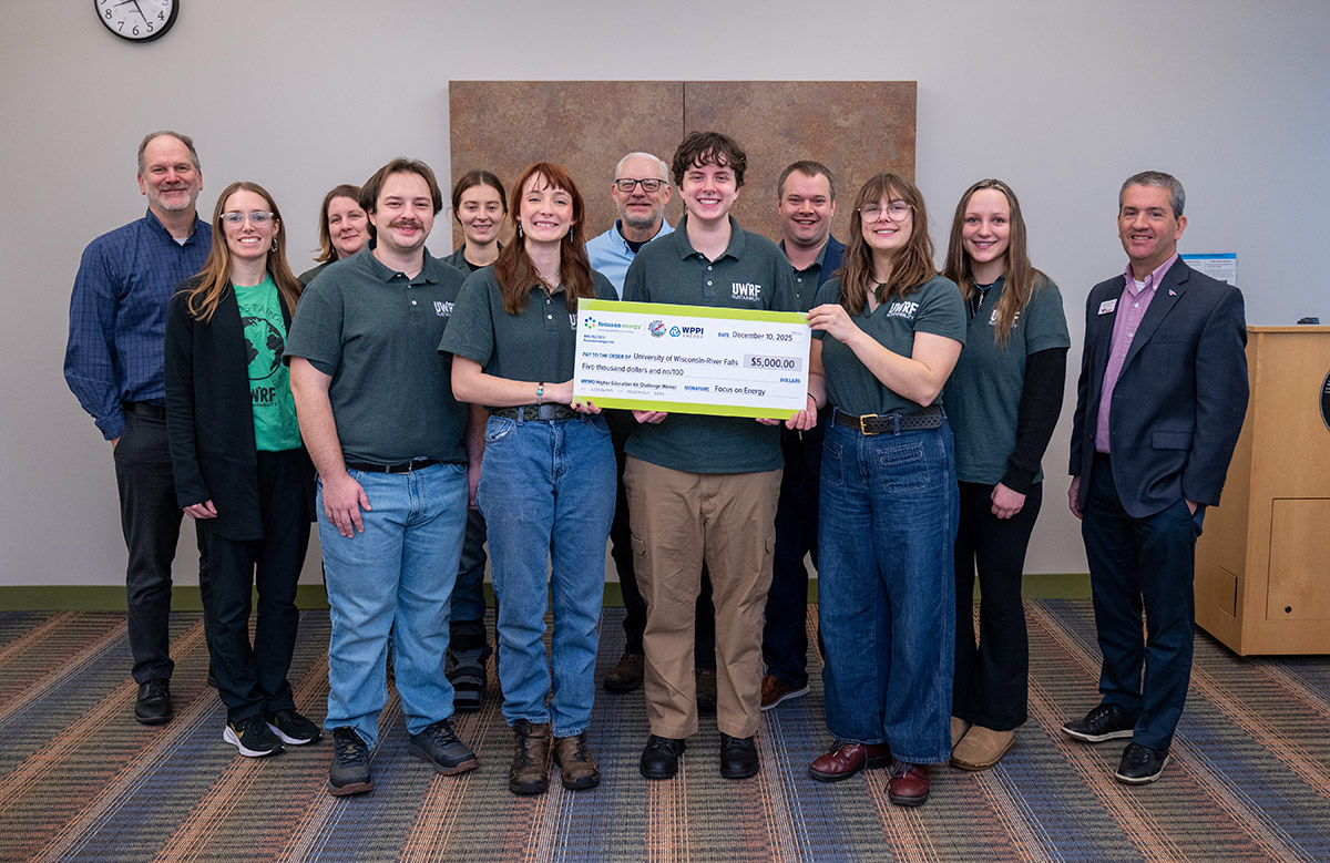 a group of students and administrators pose with an oversized check during an awards presentation