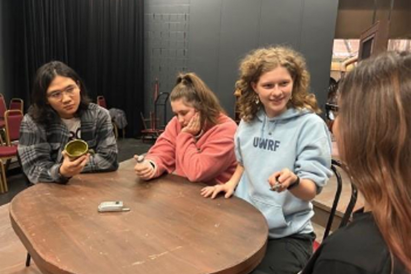 Students sitting around a table rehearsing for a play