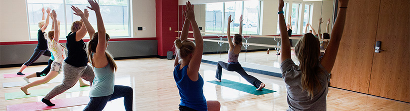 Group of students practice yoga in the Multi-Purpose room in the Falcon Center