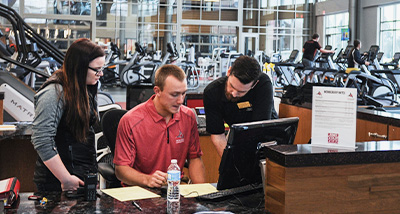 Three Falcon Center student employees stand in the student gym