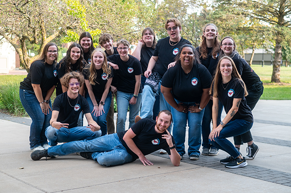 A group of students in black tshirts pose for the camera.