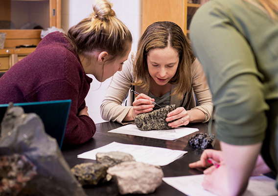 Geology professor helps students identify a specimen during lab
