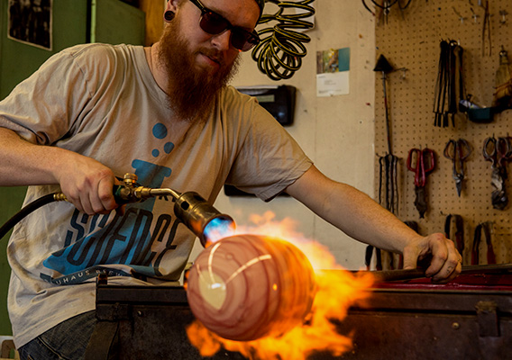 Art student works on glass vase during class