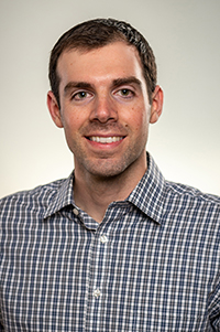 Greg Ruegsegger headshot. A white man with short brunette hair wearing a checkered button up shirt.