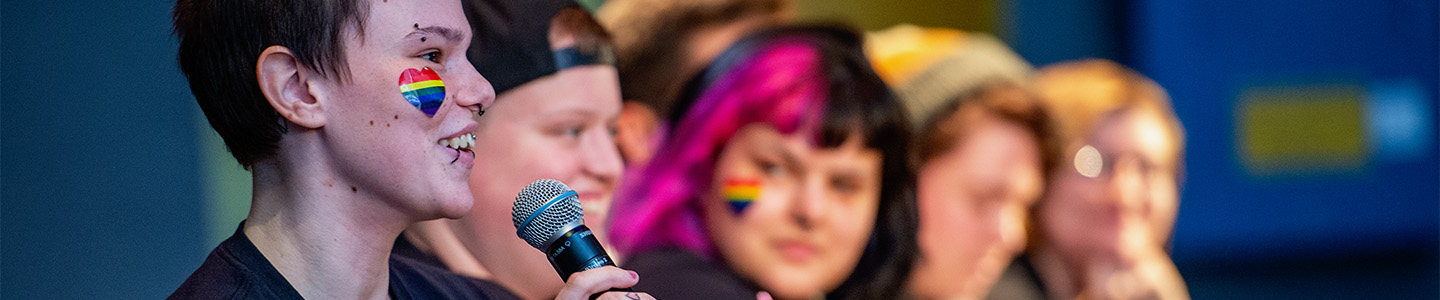 Group of students speak on stage during pride month