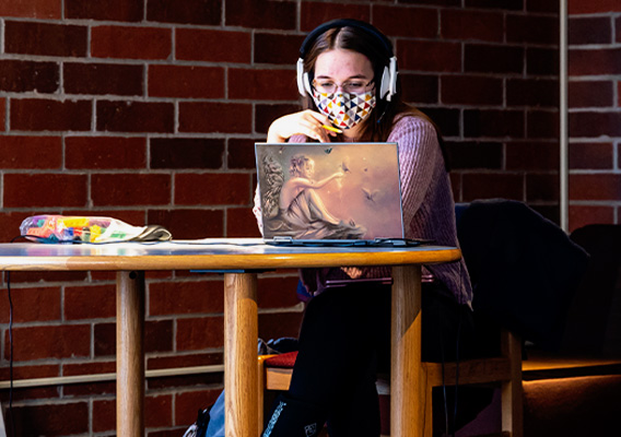 Student studies on their laptop in the campus library