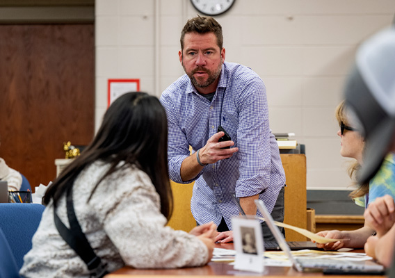 A male professor speaks to a female student during class