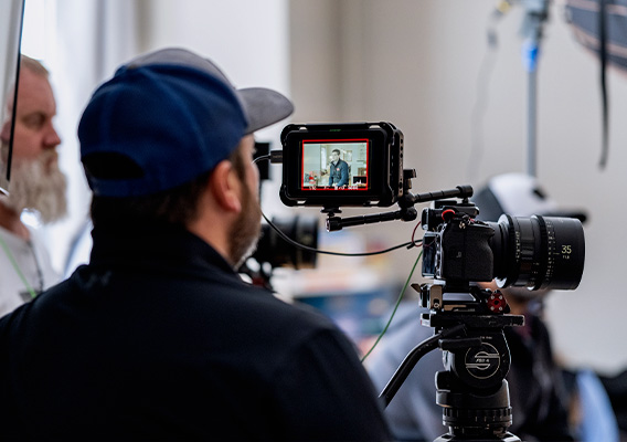 A videopgrapher sits behind a camera preparing an interview