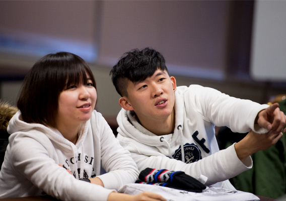 Two international students listen to a professor during class