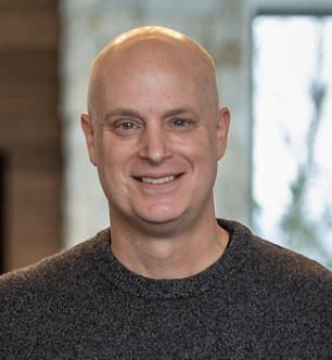 Bald white man wearing a brown sweater