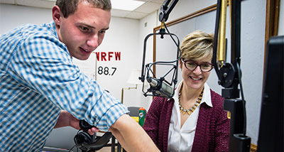 Journalism Student shows Cathy Wurzer the control panel in the broadcast room