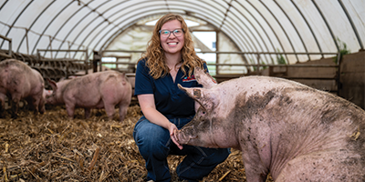 Karly in a barn with a pig