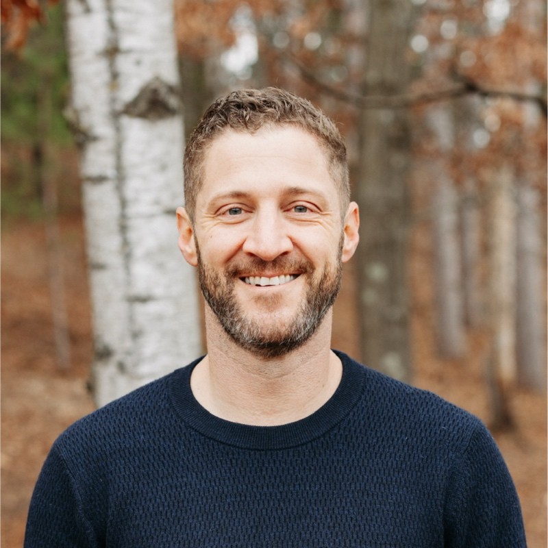 Kevin Pieh head shot. A white male with short brown hair and brown facial hair. He's standing in front of trees and wearing a navy blue sweater