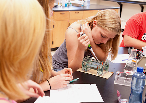 Biology student uses pipette to fill a vial during an experiment