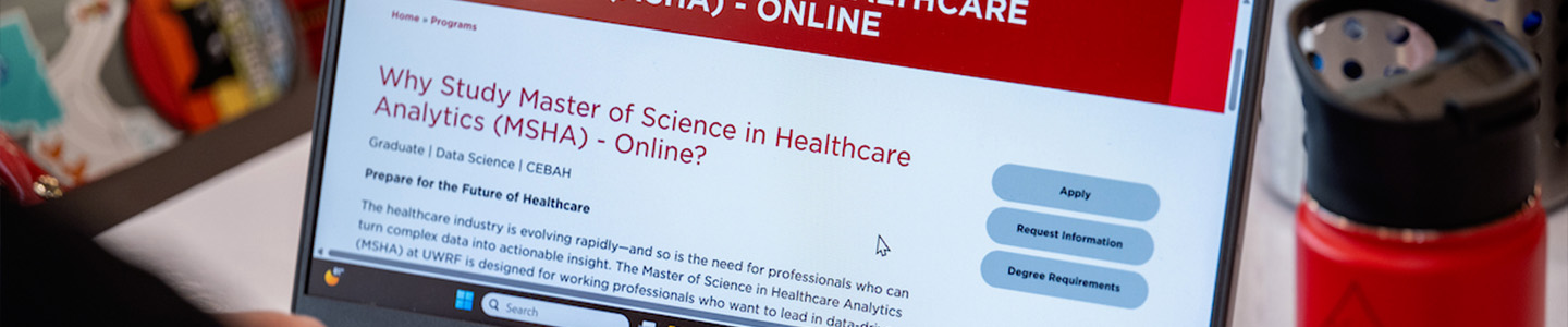 A person views a webpage talking about earning a Master of Science in Healthcare Analytics