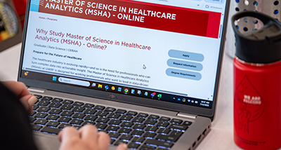 A person views a webpage talking about earning a Master of Science in Healthcare Analytics
