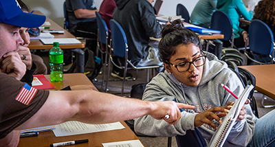 Two Mathematics students discuss notes during class