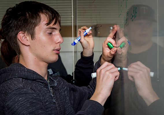 Math student writes an equation on a whiteboard