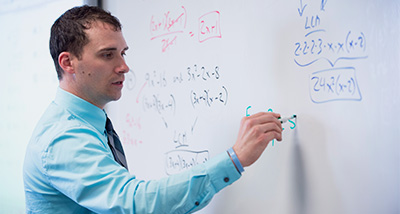 Mathematics Graduate student solves a problem on a whiteboard