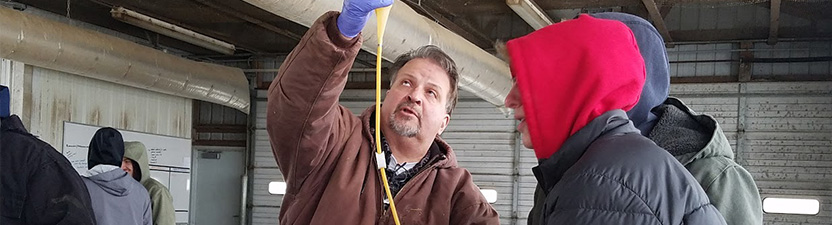 A professor hold a bottle and tube in the air so liquid can drip down