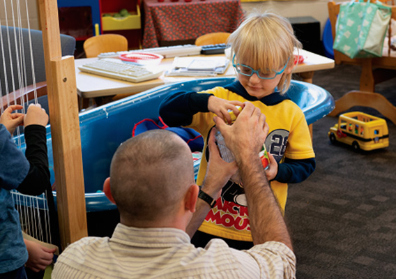 A student teacher helping a child open a jar during class time
