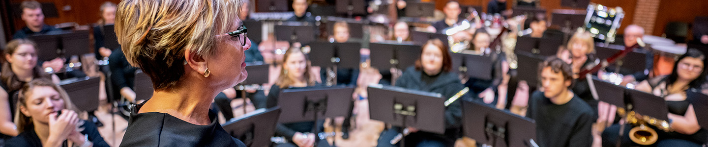 Band conductor looking out at symphony band members before they begin playing