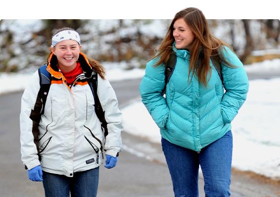 Two students walk along the path by the South Fork of the Kinnickinnic River