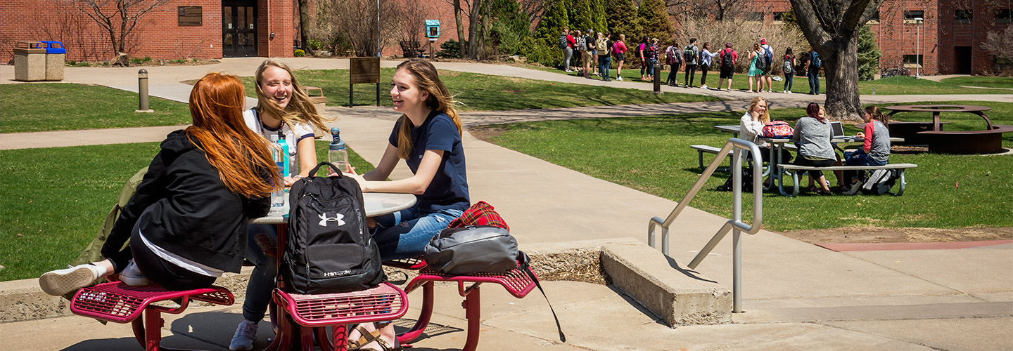 Three students enjoy the weather outside on campus