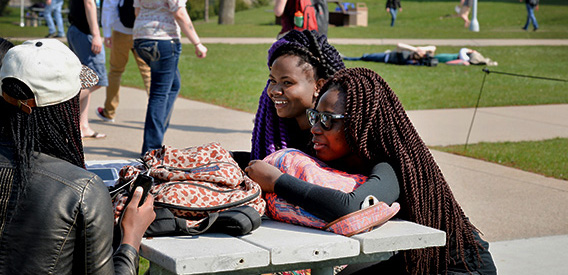Group of students sit on a picnic table on campus