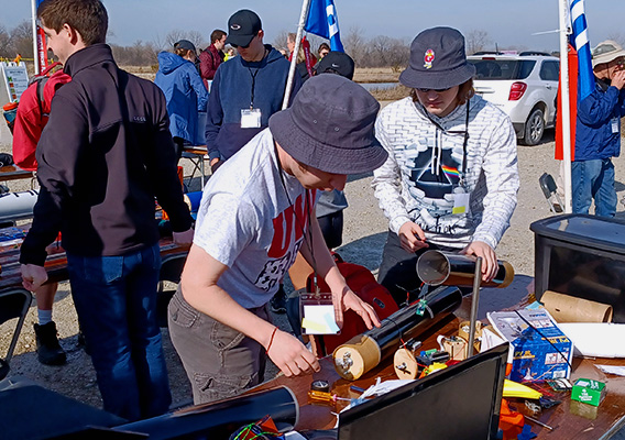 Two students conduct a rocket experiment outside during a physics class