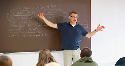 Political Science professor writing notes on a chalkboard