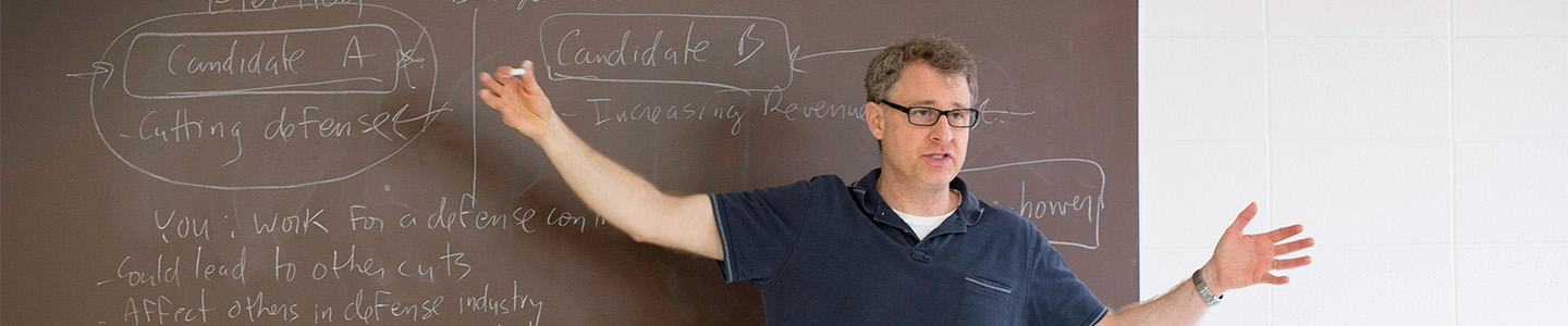 Political Science professor writing notes on a chalkboard