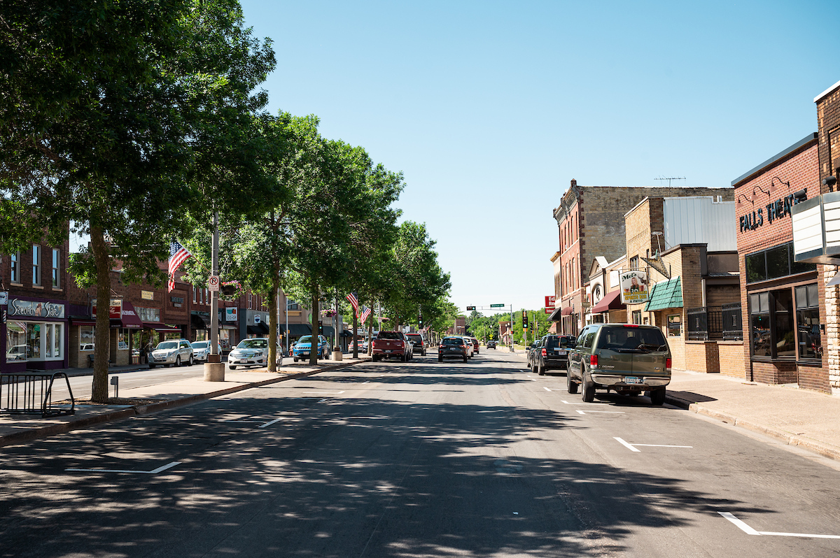 The River Falls downtown area. Main street with trees lining it and several businesses are visible.