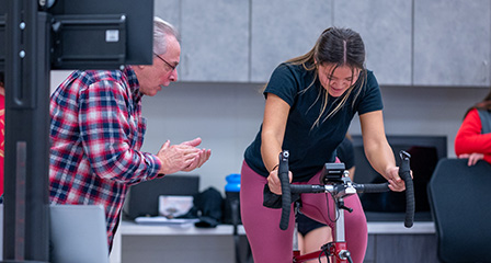 A professor cheers on a student taking part in an exercise study