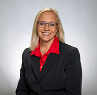 Sierra Howry headshot. A blonde woman with glasses wears a red dress shirt and black blazer.