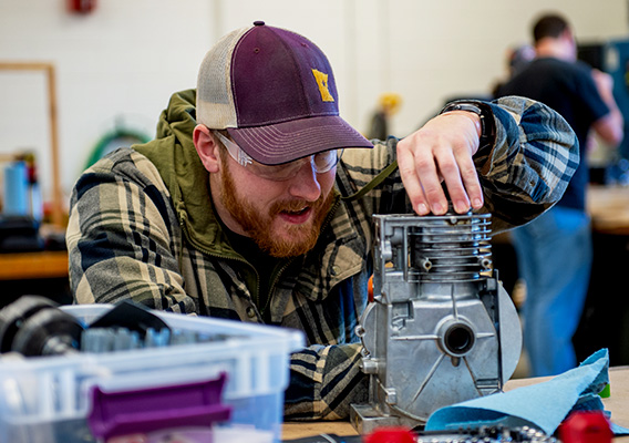 Engineering student assesses a broken small engine during class