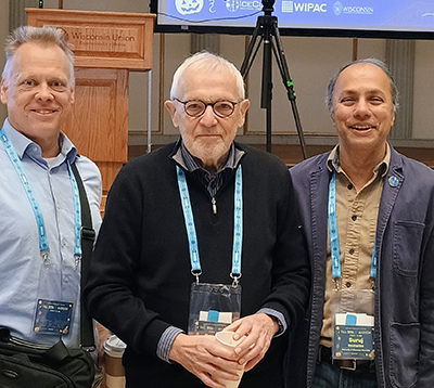 Three men pose for a photo in front of a podium.