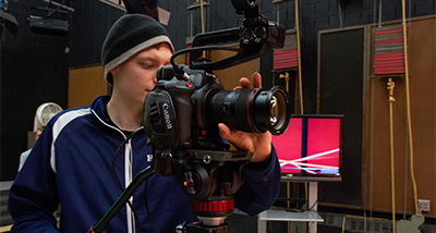 Stage and Screen Arts student looks through the lens of a camera during class
