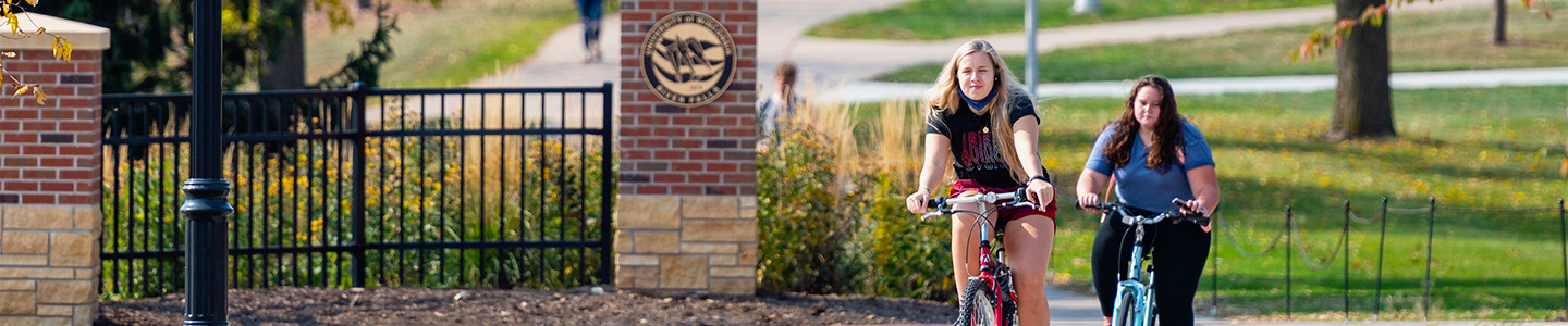 Two students bike on campus