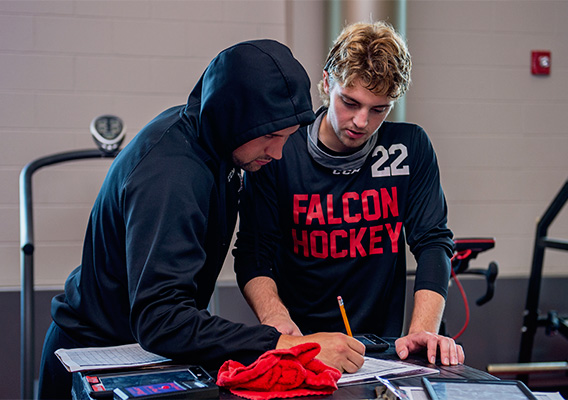 Two Strength and Conditioning Graduate students review a workout routine in the campus gym