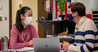 Two masked student government officials speak in a classroom