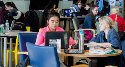 Two students work on their laptops in the University Center