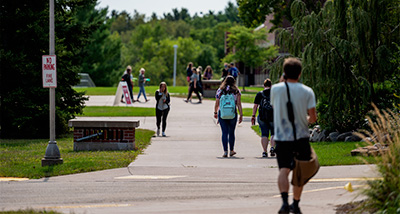Several students walk outside along the campus mall