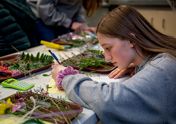 Horticulture student takes notes on flowers during class