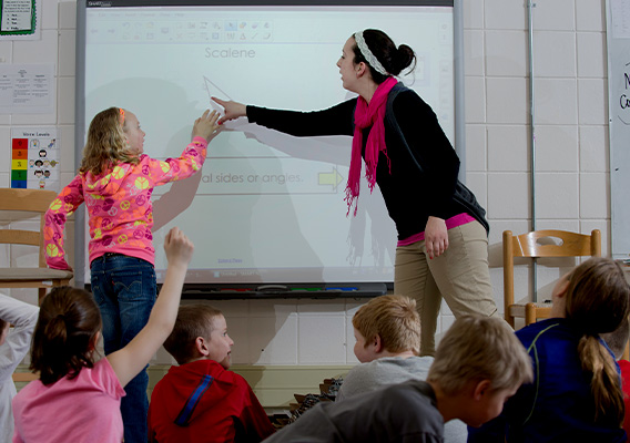 Student teacher points to information on a Smartboard during their class