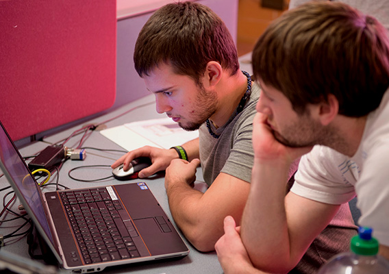 Two students look at a laptop during class