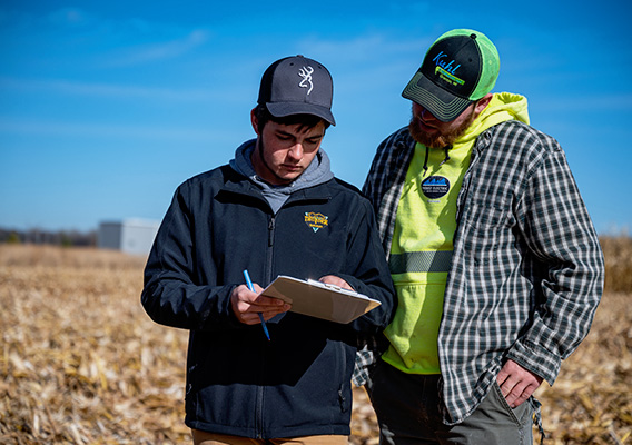 Two students assess data in a corn field