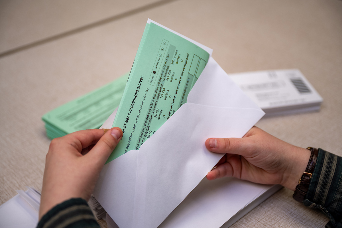 a person's hands are seen pulling a folded piece of paper out of an envelope