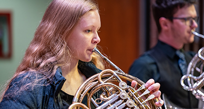 Student playing french horn with university band