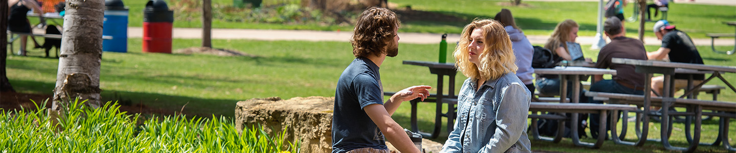 Two students hang out outside in the spring weather